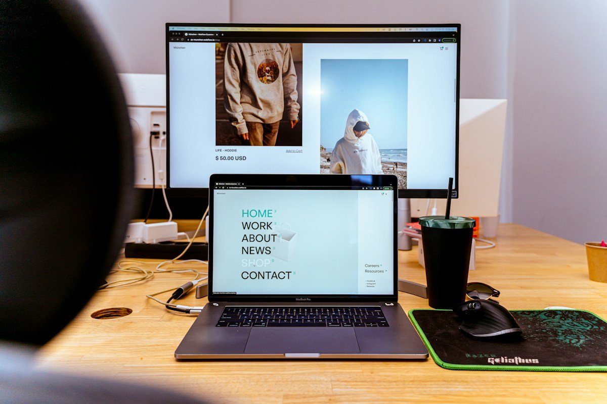 A website displayed on a laptop and desktop monitor in a design workspace